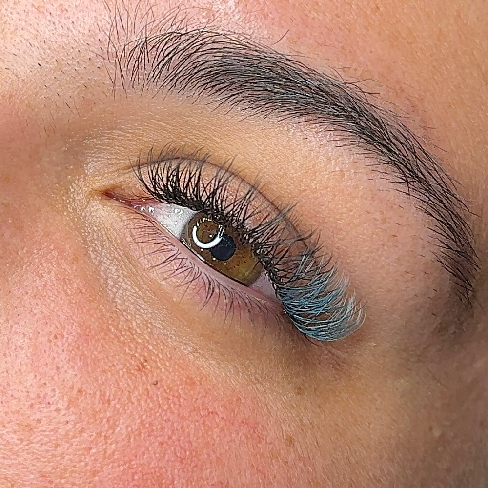 A close-up of a womans eye, showing off her new colored lash extensions.