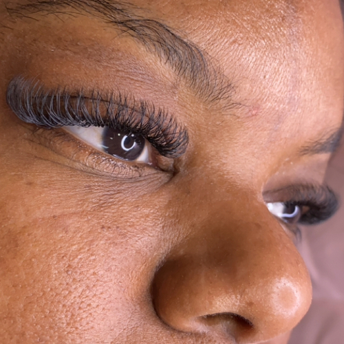 A photo of a woman laying down, showing off her new lash extensions.