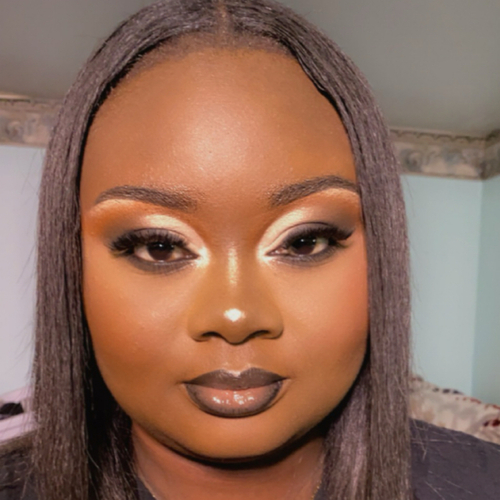 A woman sitting up, showing off her newly-done glam makeup.