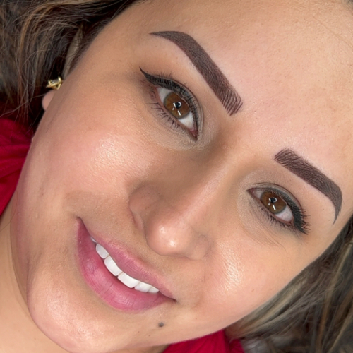 A woman laying down, showing off her newly done brow tattoo.
