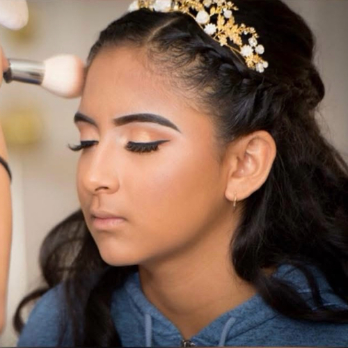 A photo of a young girl getting her makeup done for her Quinceanera.