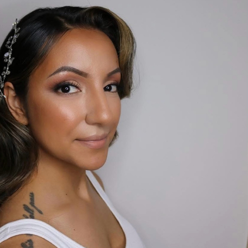 A woman standing off to the side of the photo. She is looking into the camera showing off her bridal makeup.