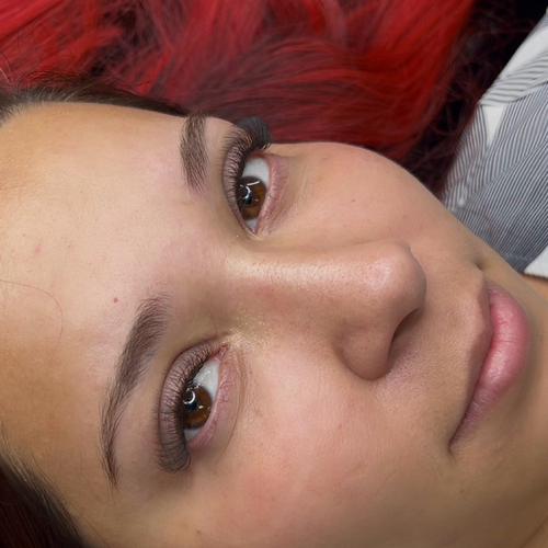 A photo of a woman laying down, showing off her new lash extensions.