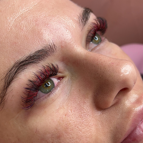 A woman laying down showing off her red colored eyelashes.
