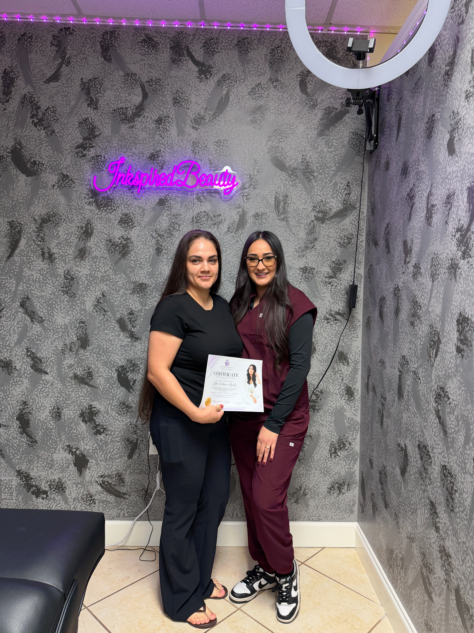 Lash Class Student holding her lash certificate of completion, with owner and teacher Nancy of Inkspired Beauty.