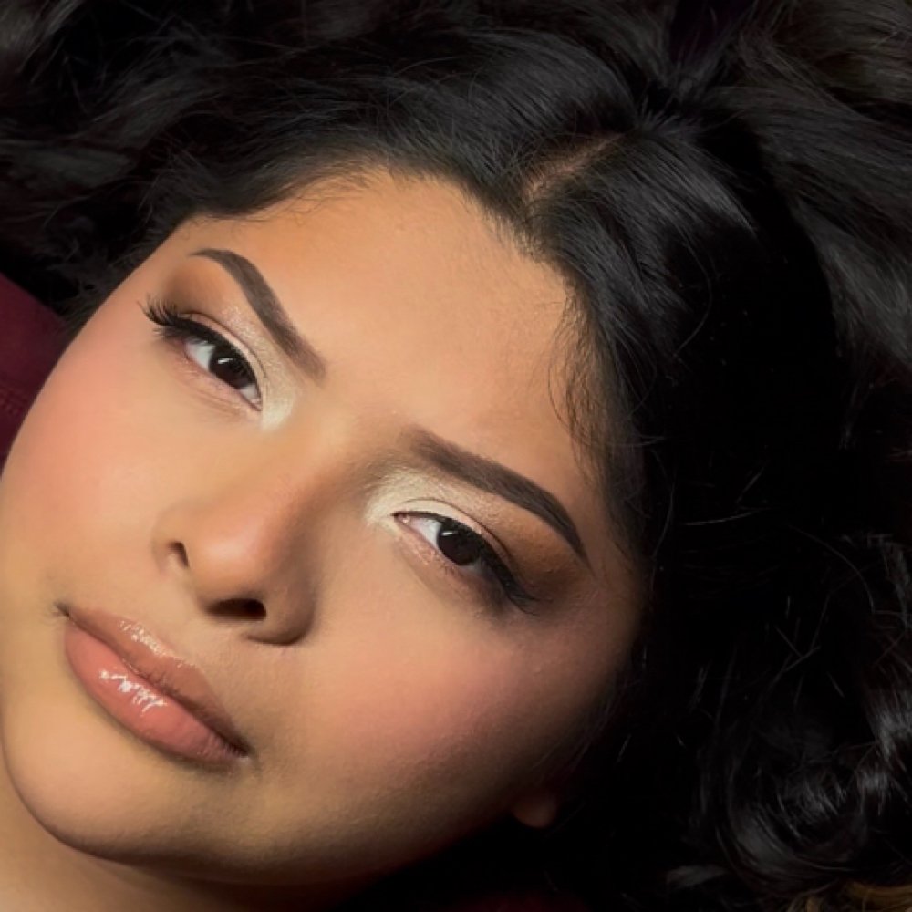 A woman posing, showing off her soft glam makeup.